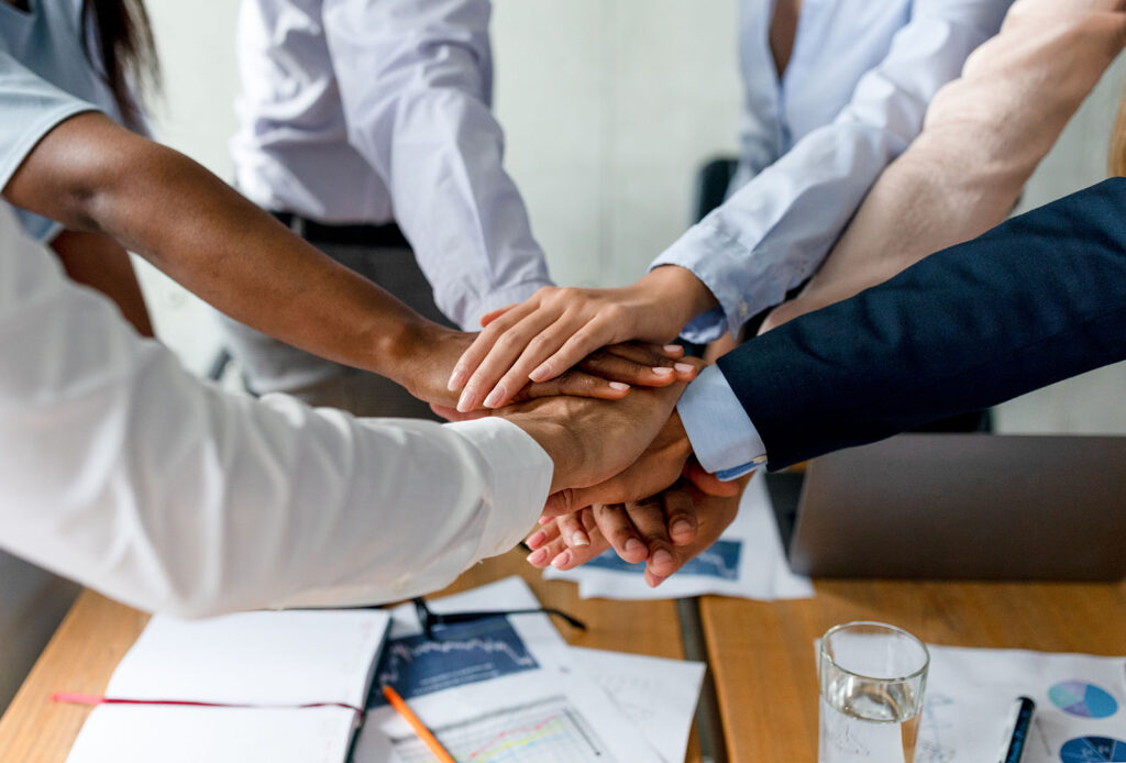 Teamwork Success. Multiethnic Group Of Colleagues Stacking Hands Together In Office
